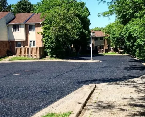Image depicts a parking lot with new asphalt sealing.